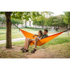 Couple enjoying hammock between trees at park