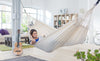 Woman reading a book in a comfortable white hammock