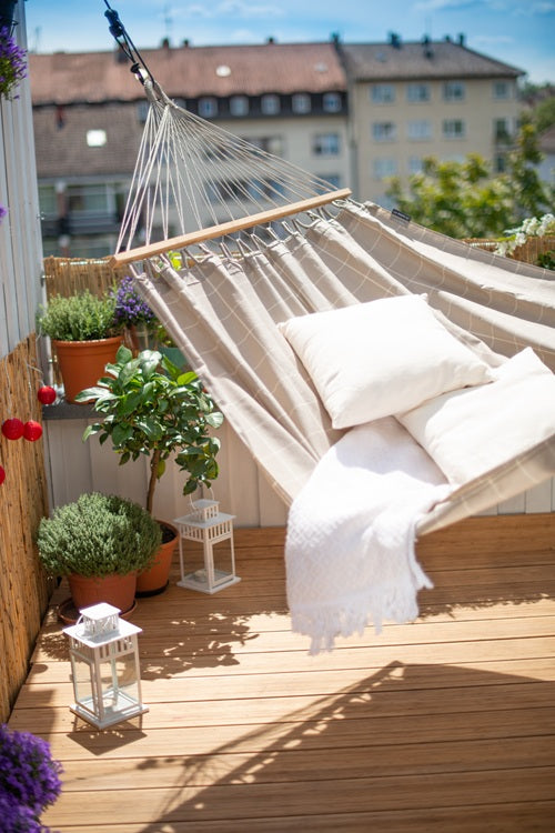 Hammock on a wooden deck with plants and lanterns