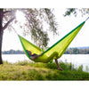 Man relaxing with beer in hammock by lake