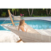 Woman relaxing with drink in hammock beside pool