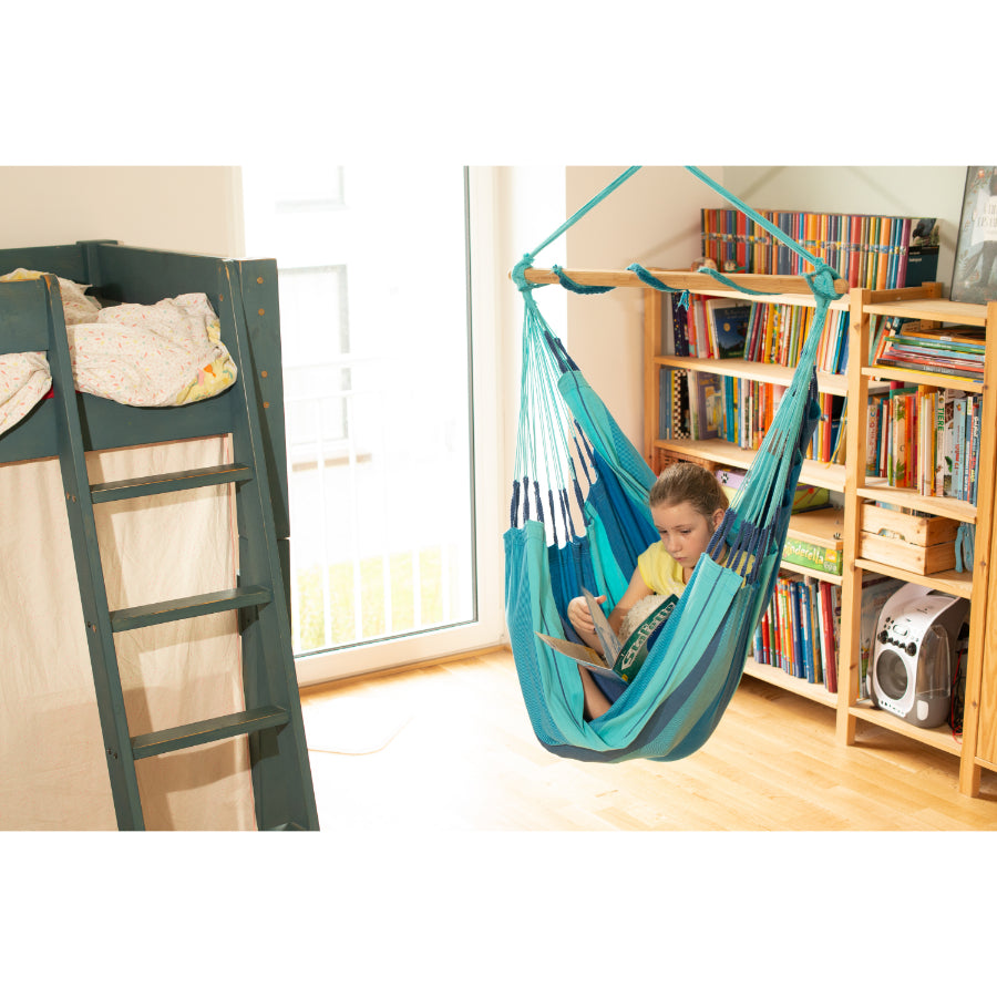 young girl reading in blue hammock chair in bedroom