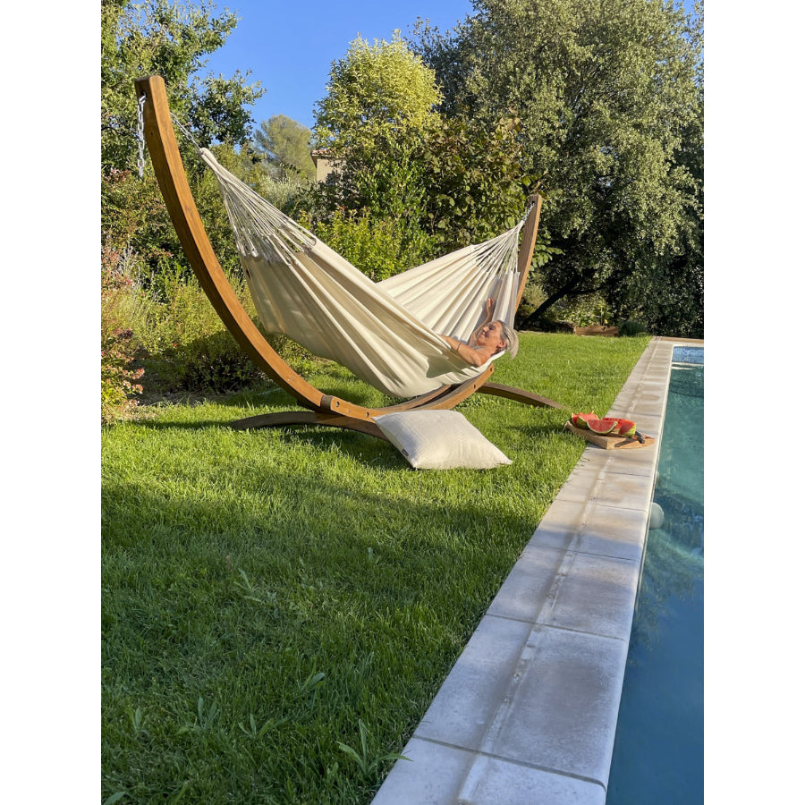 White hammock on wooden frame beside pool