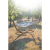 Curved wooden hammock stand in forest with blue and white hammock