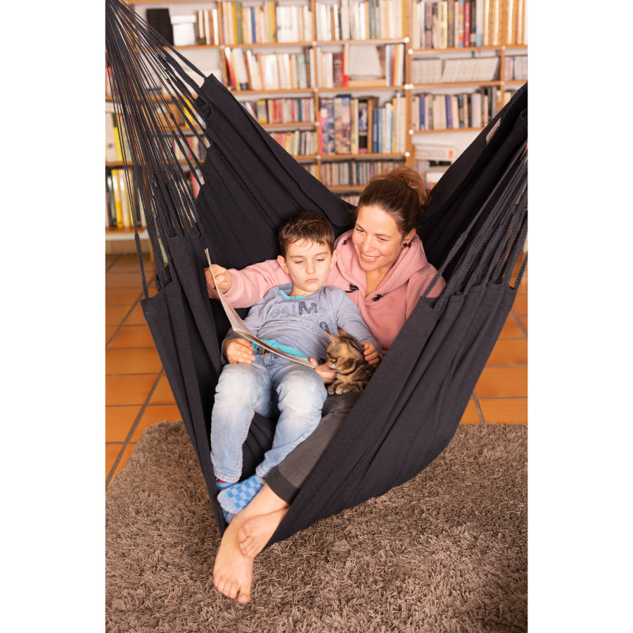 Mother and son reading book together in black chair hammock