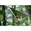 Woman resting in the forest on a hammock drinking water